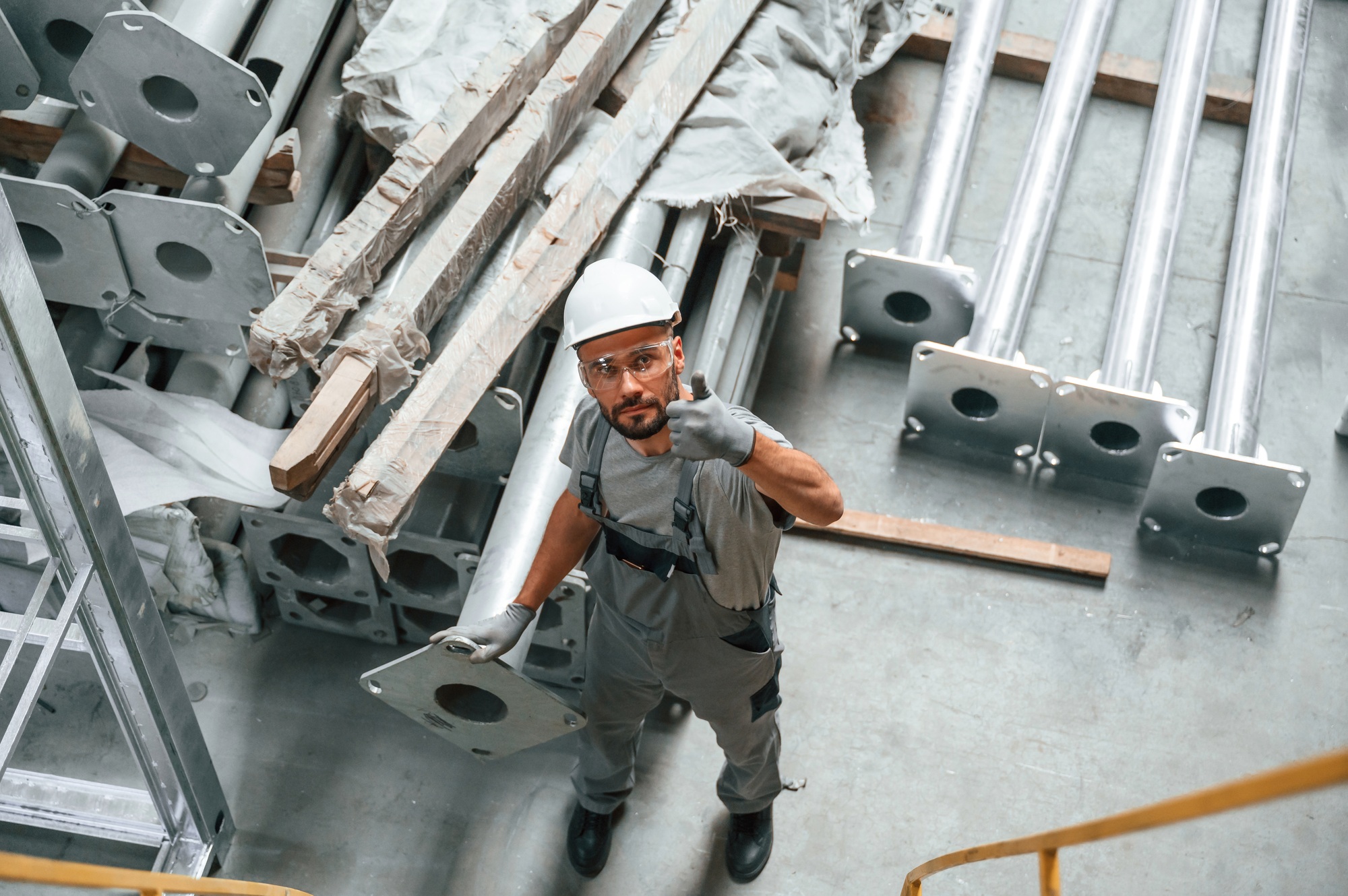 Top view. Making gesture by hands. Young factory worker in grey uniform