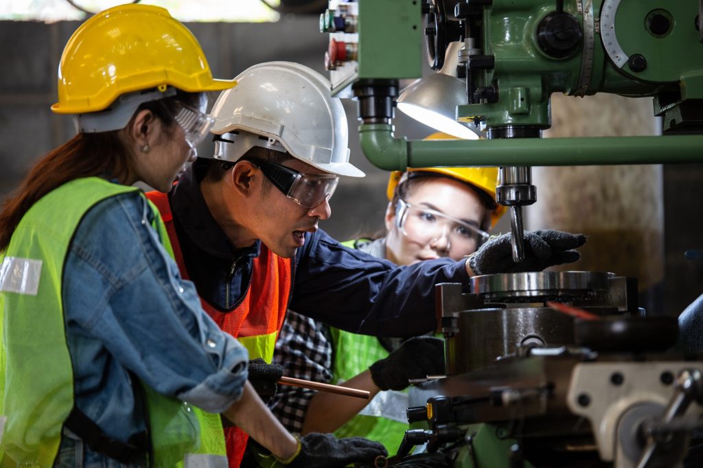 Asian foreman training female trainee worker with the machine