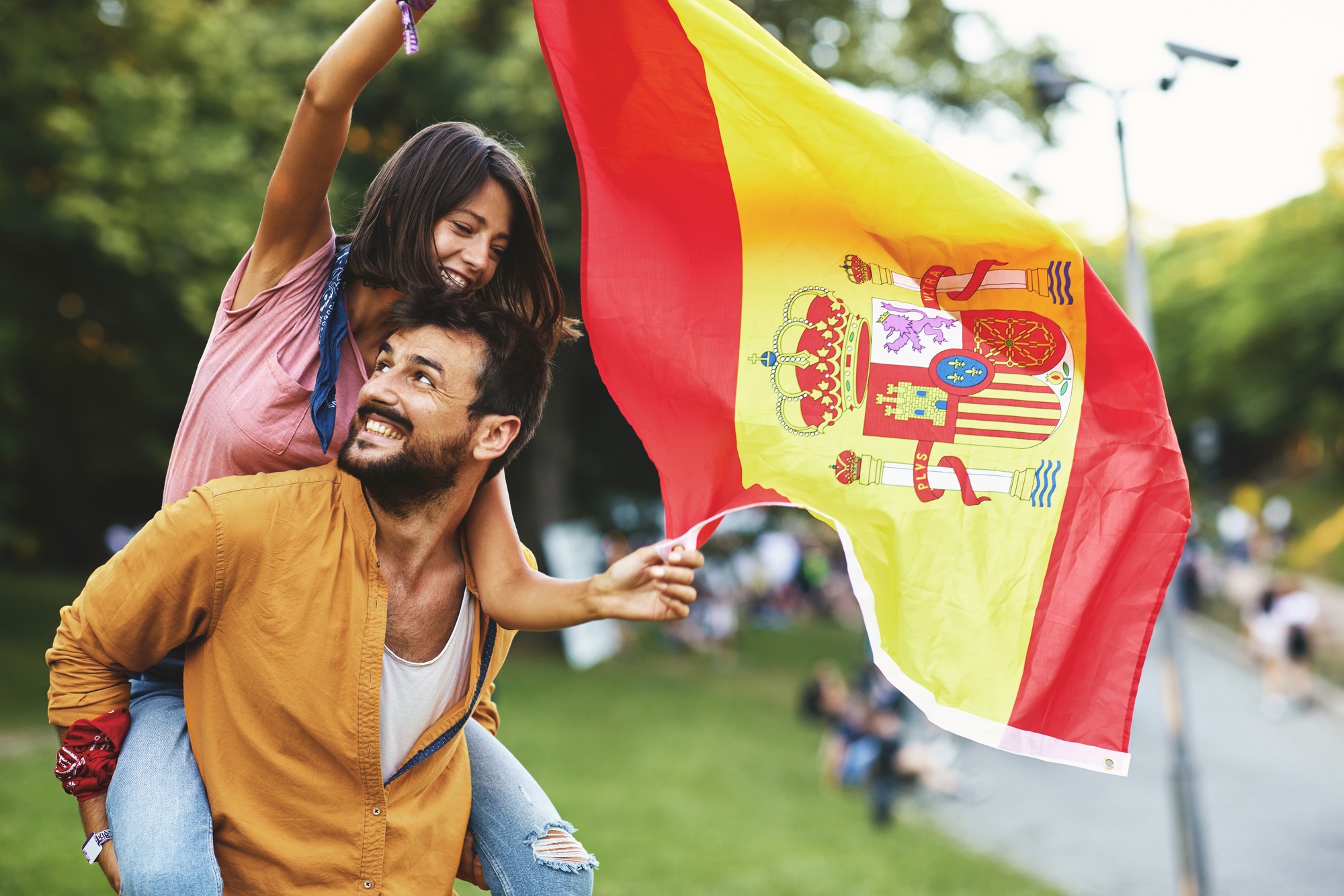 Young couple dancing in the park at a festival with a Spanish national flag